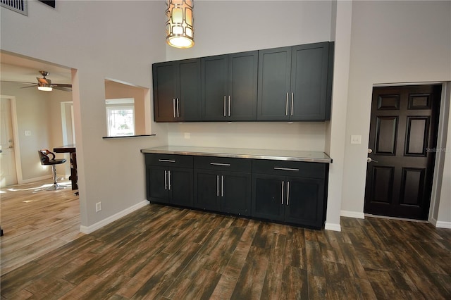 kitchen with dark hardwood / wood-style floors, ceiling fan, and a towering ceiling