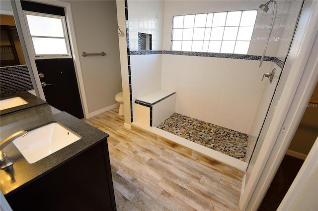 bathroom featuring vanity, hardwood / wood-style flooring, toilet, and tiled shower