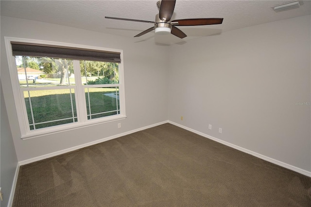 spare room with ceiling fan, a textured ceiling, and dark colored carpet