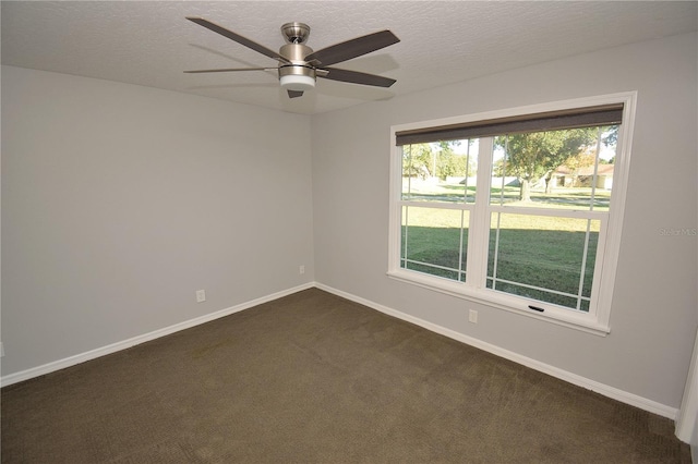 spare room featuring ceiling fan, a textured ceiling, and dark carpet