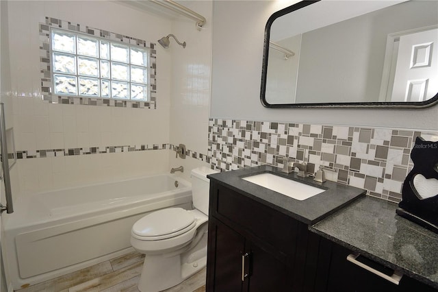 full bathroom featuring tile walls, tiled shower / bath combo, vanity, hardwood / wood-style flooring, and toilet