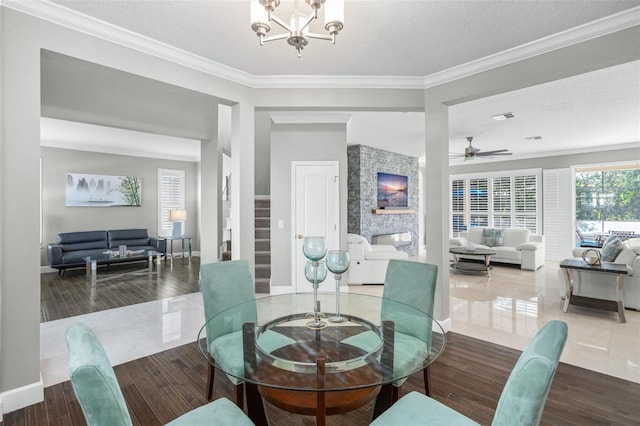 dining room with a stone fireplace, wood-type flooring, a textured ceiling, and ornamental molding