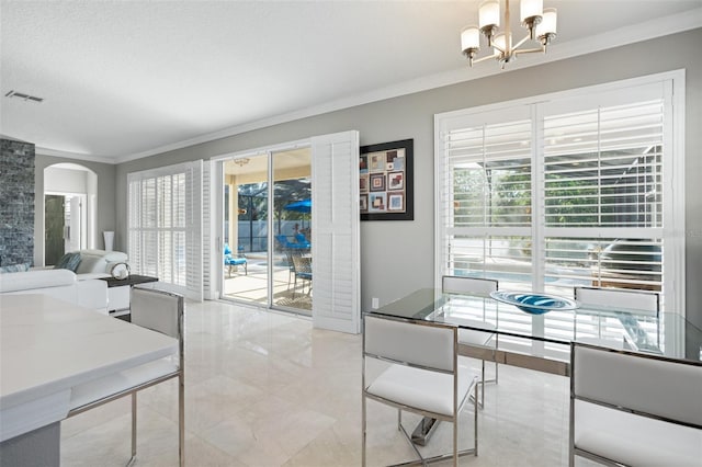 dining space featuring ornamental molding, a textured ceiling, and a notable chandelier