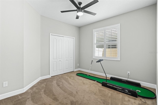 exercise area with carpet flooring, ceiling fan, and a textured ceiling