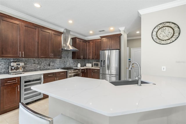 kitchen featuring appliances with stainless steel finishes, light stone counters, wall chimney exhaust hood, sink, and wine cooler