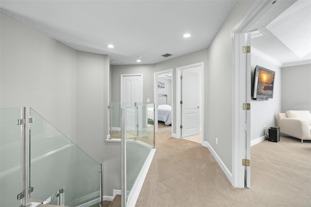 corridor featuring light colored carpet and a textured ceiling