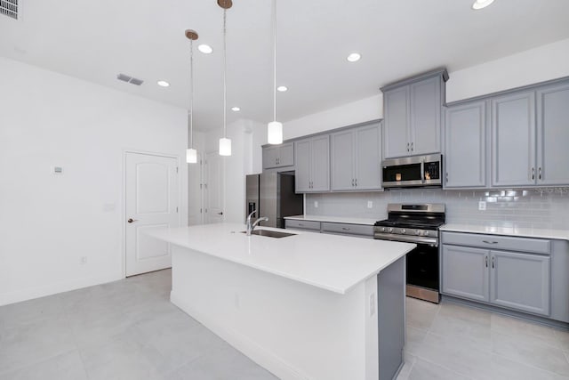 kitchen with tasteful backsplash, stainless steel appliances, sink, pendant lighting, and an island with sink