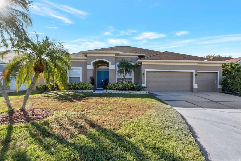 single story home with a garage and a front lawn