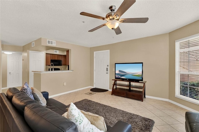 tiled living room featuring a textured ceiling and ceiling fan