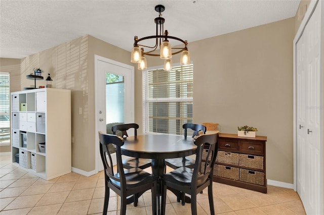 tiled dining room featuring a textured ceiling and a notable chandelier