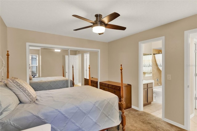 carpeted bedroom featuring a closet, ensuite bathroom, and ceiling fan