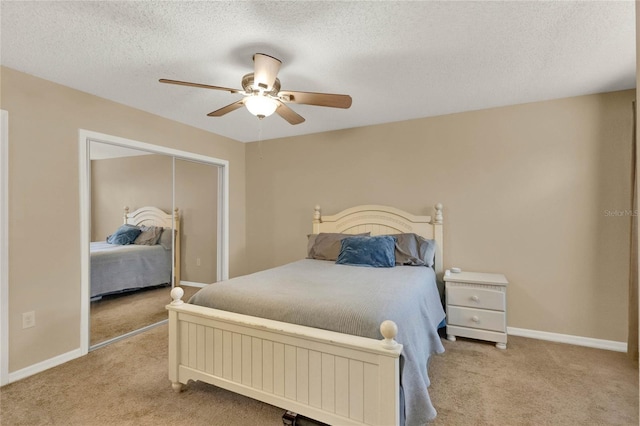 bedroom with a textured ceiling, light colored carpet, a closet, and ceiling fan