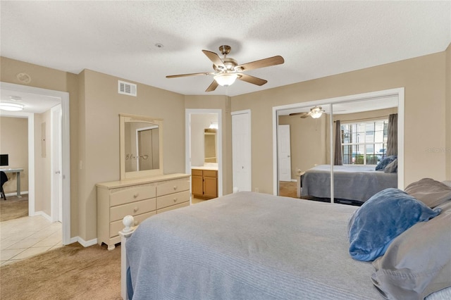 carpeted bedroom featuring ensuite bath, ceiling fan, and a textured ceiling