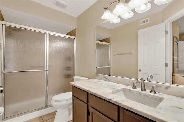 bathroom featuring tile patterned floors, vanity, a shower with shower door, and toilet