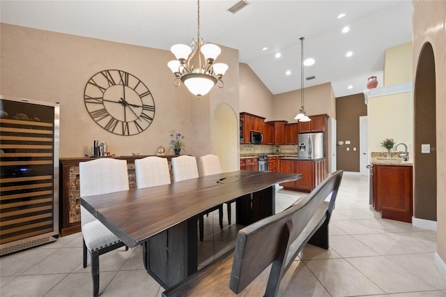 dining space featuring a chandelier, high vaulted ceiling, beverage cooler, and light tile patterned floors