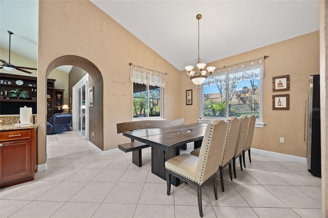 tiled dining space featuring high vaulted ceiling and ceiling fan with notable chandelier