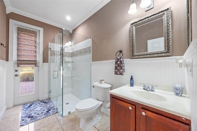 bathroom featuring vanity, a shower with door, tile patterned floors, crown molding, and toilet