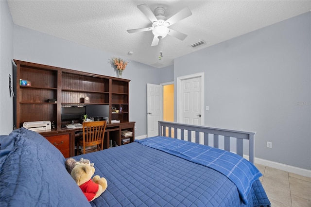 bedroom with ceiling fan, light tile patterned floors, and a textured ceiling