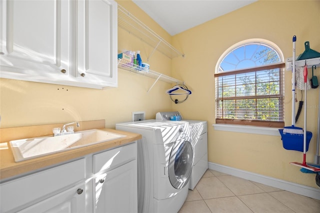 clothes washing area featuring washer and dryer, cabinets, light tile patterned floors, and sink