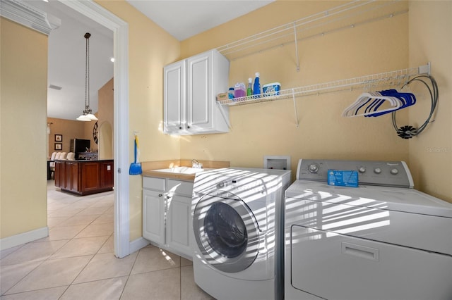 laundry area featuring washer and clothes dryer, light tile patterned flooring, cabinets, and sink