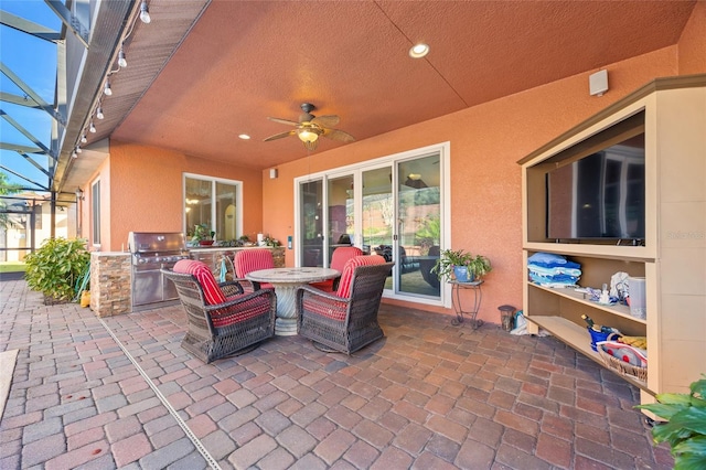 view of patio with an outdoor kitchen, area for grilling, ceiling fan, and a lanai