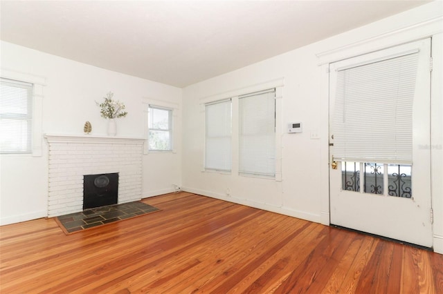 unfurnished living room with hardwood / wood-style flooring and a brick fireplace