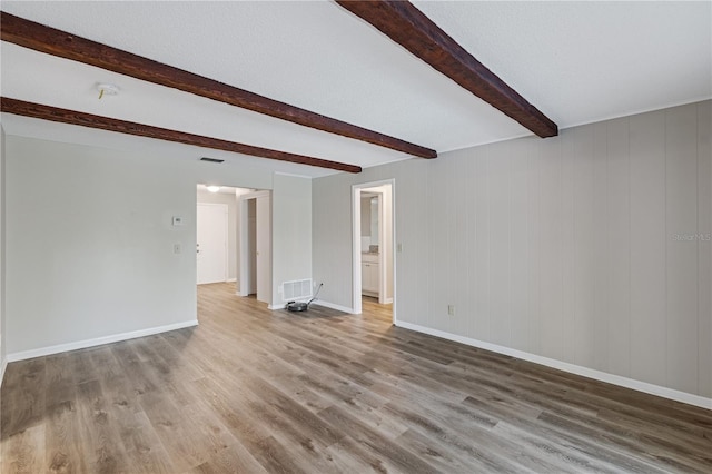 unfurnished room featuring beamed ceiling, hardwood / wood-style floors, and wooden walls