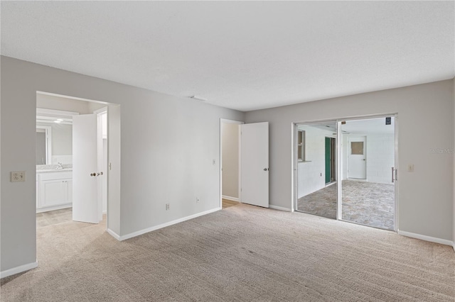 unfurnished bedroom featuring ensuite bathroom, light colored carpet, and a closet