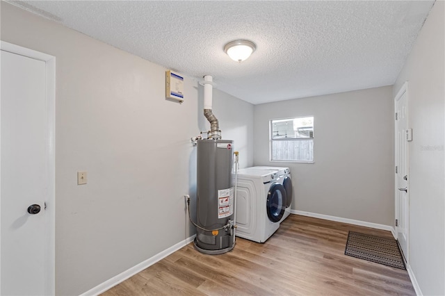 laundry area featuring light wood-type flooring, separate washer and dryer, a textured ceiling, and water heater