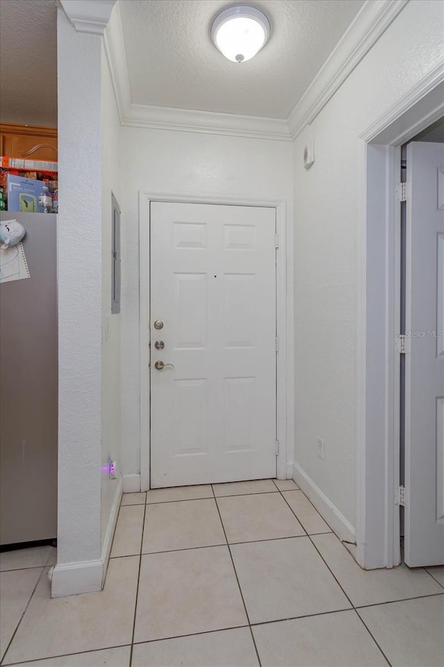 entryway with light tile patterned floors, a textured ceiling, and ornamental molding