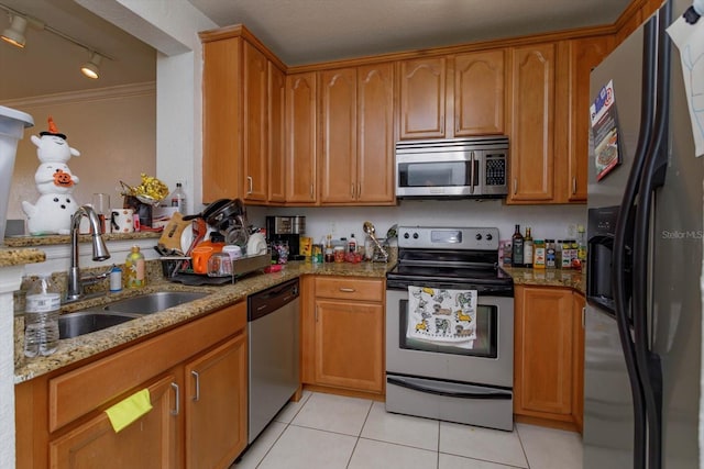 kitchen featuring sink, light stone counters, track lighting, light tile patterned flooring, and appliances with stainless steel finishes