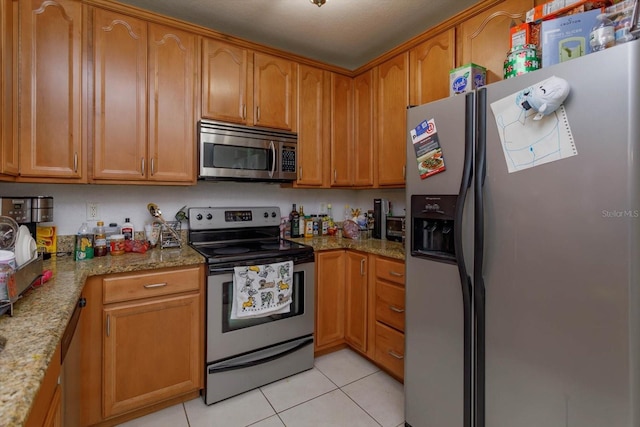 kitchen with light stone counters, light tile patterned floors, and stainless steel appliances