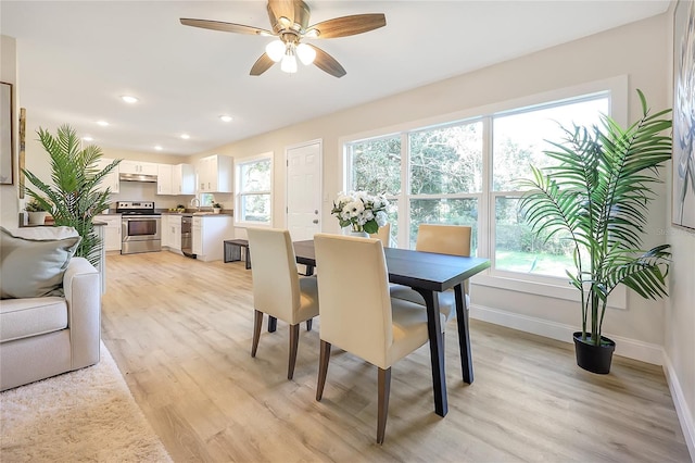 dining area with ceiling fan, light hardwood / wood-style floors, and sink