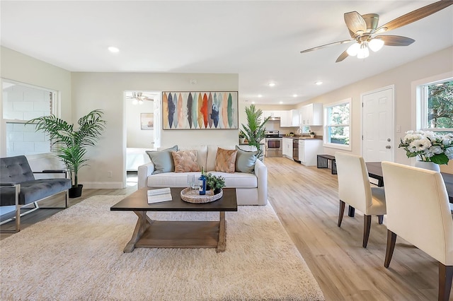 living room with a healthy amount of sunlight, ceiling fan, and light hardwood / wood-style floors