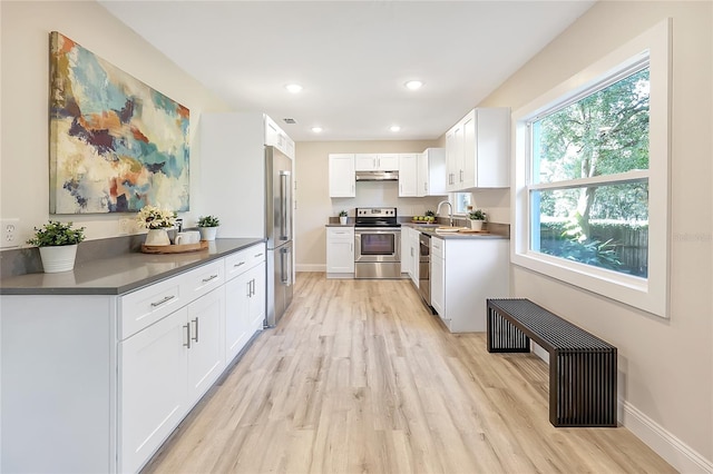 kitchen with white cabinets, light wood-type flooring, stainless steel appliances, and sink