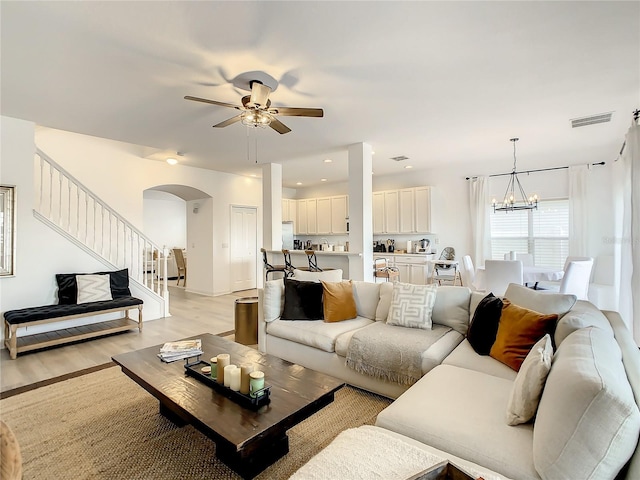 living room featuring light wood-type flooring and ceiling fan with notable chandelier