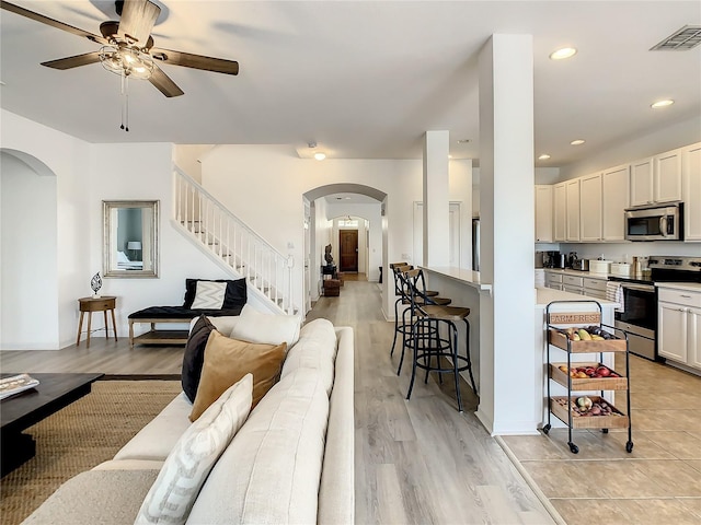 living room with ceiling fan and light hardwood / wood-style flooring