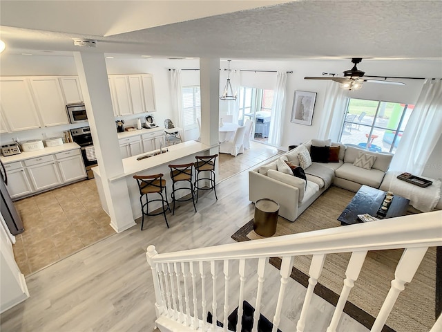 living room with ceiling fan, light hardwood / wood-style floors, a textured ceiling, and a wealth of natural light