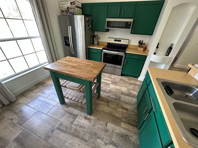 kitchen featuring sink, stainless steel appliances, a wealth of natural light, and green cabinetry