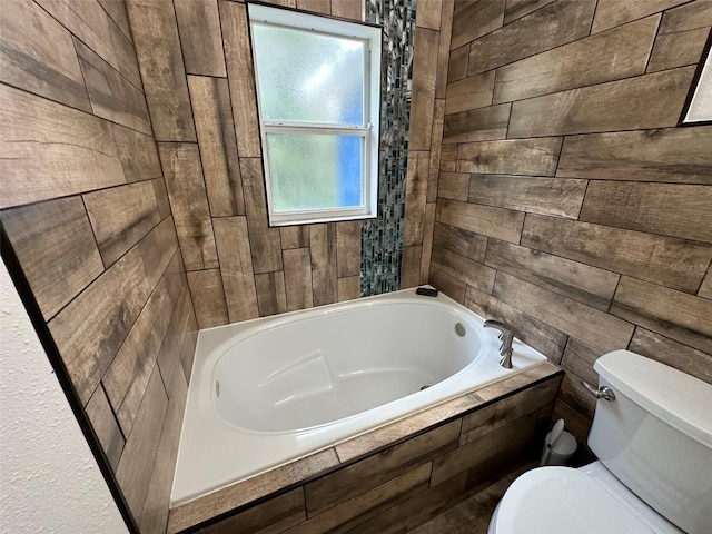 bathroom with a relaxing tiled tub and toilet