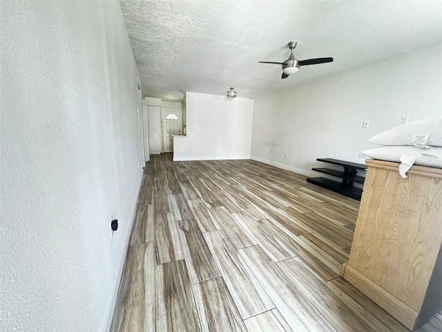 unfurnished living room with ceiling fan, wood-type flooring, and a textured ceiling