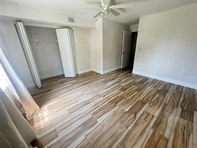 unfurnished bedroom with a textured ceiling, a closet, light hardwood / wood-style flooring, and ceiling fan