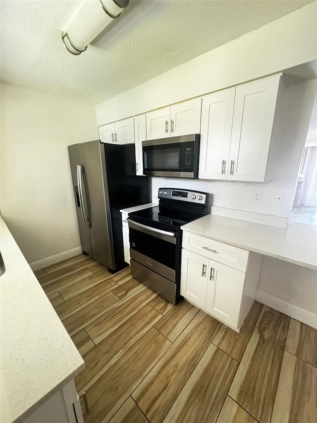 kitchen featuring light hardwood / wood-style floors, white cabinetry, a textured ceiling, and appliances with stainless steel finishes