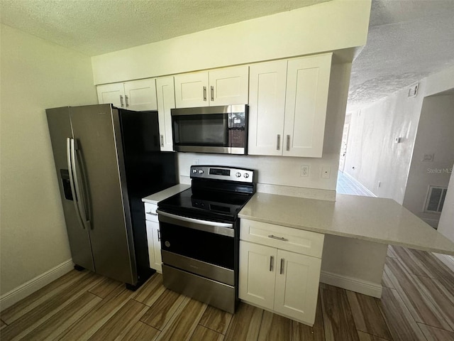 kitchen featuring white cabinets, light hardwood / wood-style floors, a textured ceiling, and appliances with stainless steel finishes