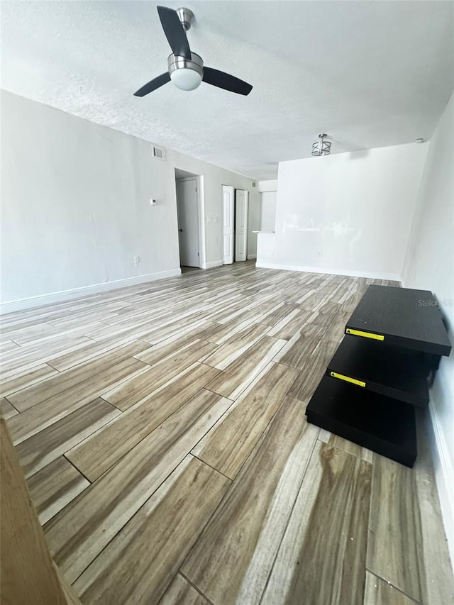 interior space with ceiling fan, wood-type flooring, and a textured ceiling