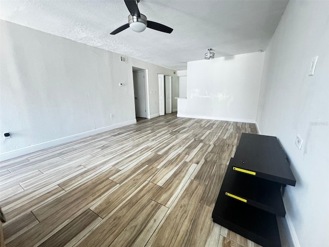 unfurnished living room featuring ceiling fan, light hardwood / wood-style flooring, and a textured ceiling