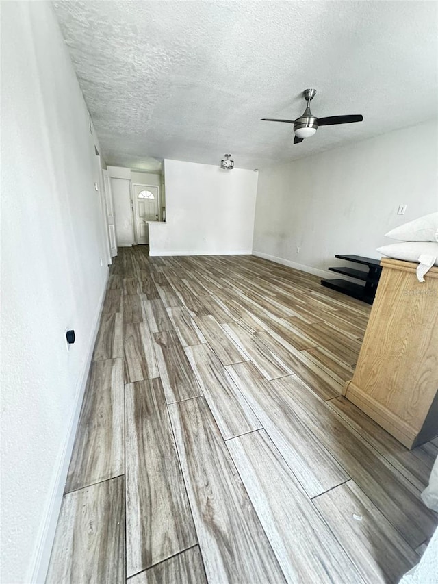 unfurnished living room with wood-type flooring, a textured ceiling, and ceiling fan