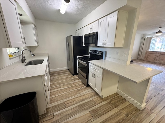 1234 Sago Palm Blvd Unit 1234, Kissimmee, FL 34741 - kitchen featuring stainless steel appliances, a sink, light wood-style flooring, a peninsula, and a textured ceiling