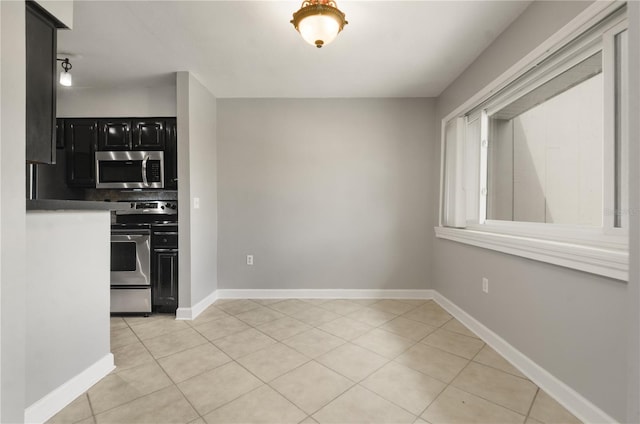 5929 Windhover Dr Unit A02, Orlando, FL 32819 - kitchen featuring stainless steel appliances, dark cabinetry, light tile patterned floors, and tasteful backsplash