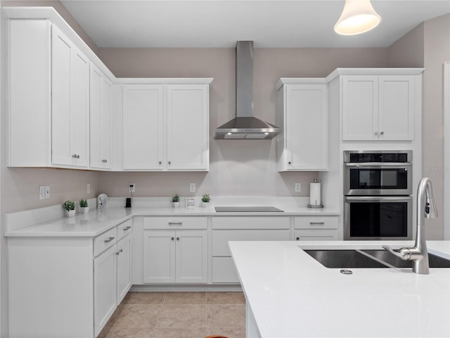 kitchen featuring stovetop, white cabinetry, wall chimney range hood, and sink